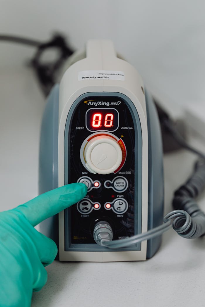 services-01 Green-gloved hand adjusting settings on modern medical equipment control panel.