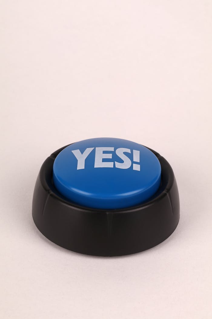 about-01 A blue yes button with black base on a beige background, perfect for communication concepts.